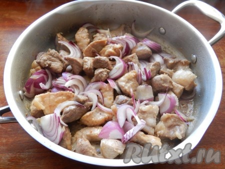 Уменьшить огонь до среднего, выложить в сковороду лук и обжарить его вместе с мясом около 5 минут.